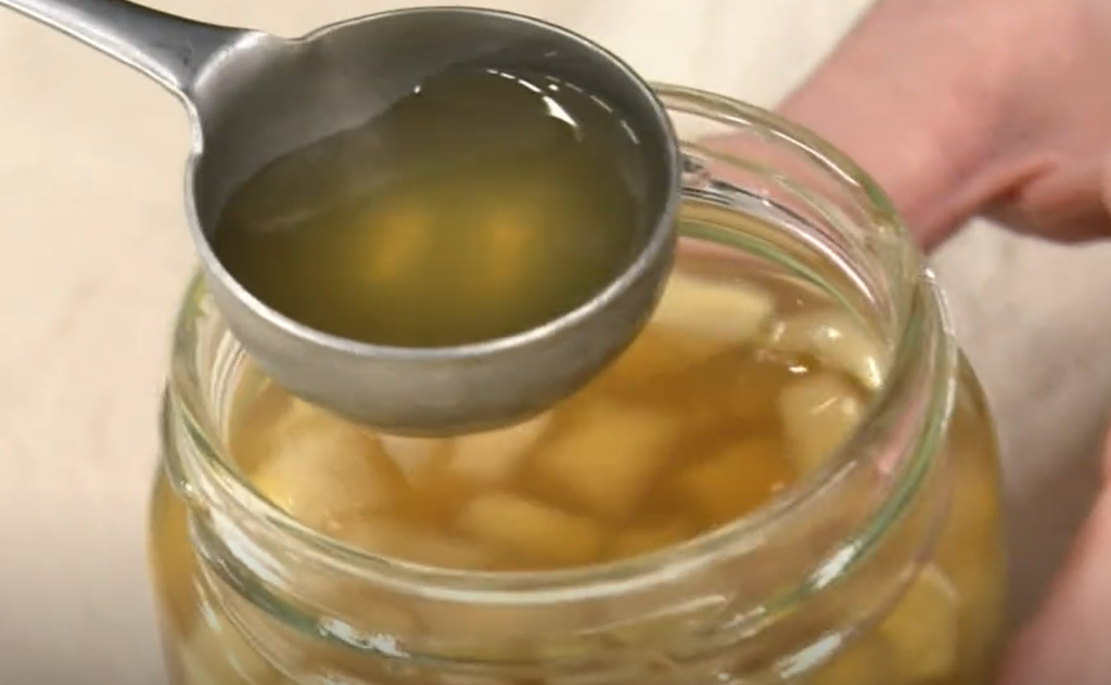 角切りの大根とはちみつを瓶に漬けた“大根あめ”をスプーンですくっている画像。